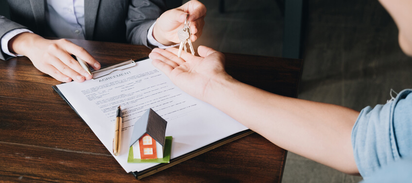 A real estate agent giving the house keys to the new homeowner after signing the closing agreement