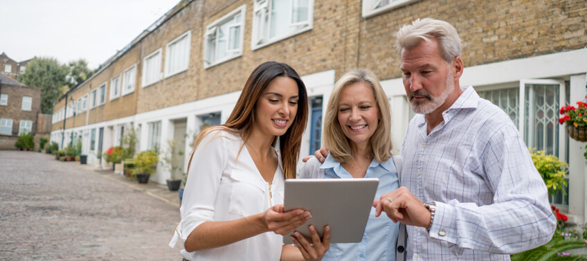 A realtor showing a real estate contract through her tablet to an old couple