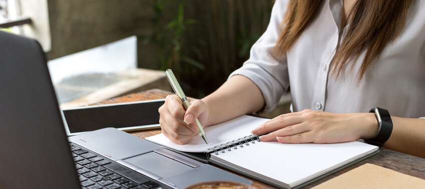 A woman taking down notes about how to write real estate agent bio