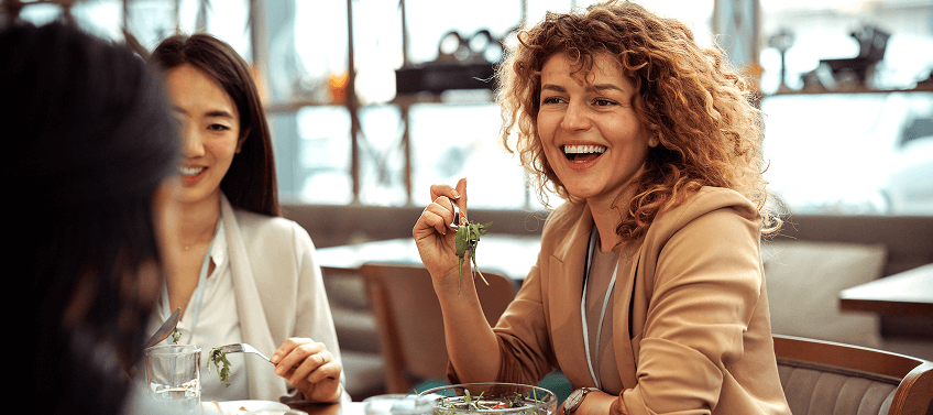 Three professionally dressed women enjoying lunch together at an upscale dining spot.