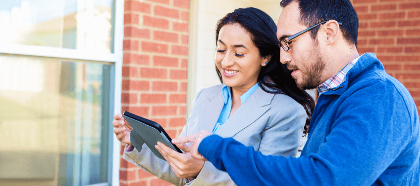 Two real estate agents, male and female, looking at a tablet screen.