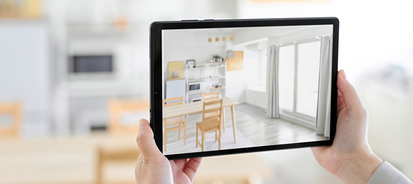 A woman uses an augmented reality app to simulate furniture placement in a home.