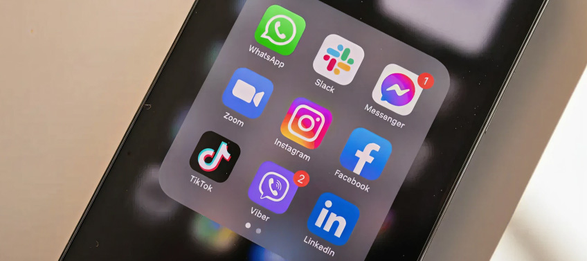 A mobile device with a folder of different social apps, including Messenger, Instagram, Facebook, and TikTok.