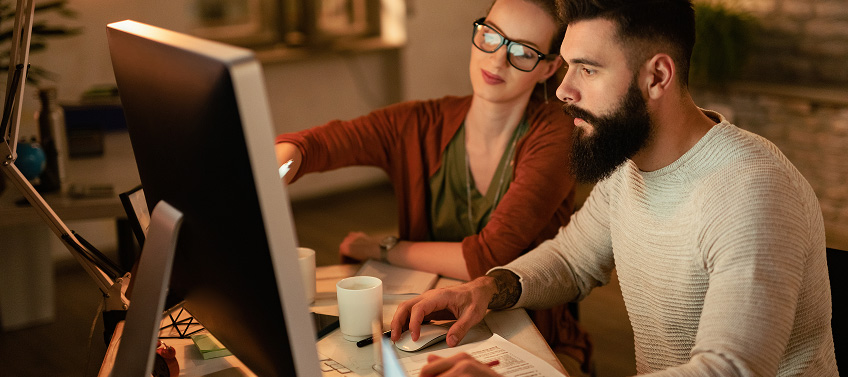 Two professionals sitting in front of a computer choosing an image.
