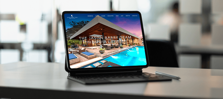 Tablet displaying The Jason Barry Team real estate website, an Agent Image-designed site, on a desk in a bright workspace